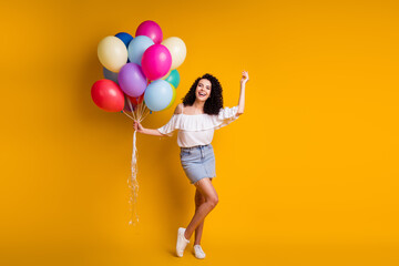 Fototapeta na wymiar Full size photo of content pretty girl hold many balloons wear good look outfit isolated over vivid yellow color background