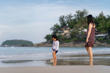 Mother and daughter standing at sea shore in Phuket Thailand.