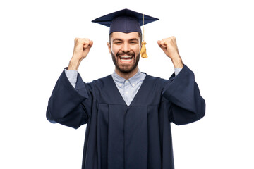 education, graduation and people concept - happy smiling male graduate student in mortar board and bachelor gown celebrating success over grey background