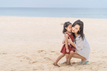 Fototapeta na wymiar Beautiful Young mother and daughter sitting at the beach.