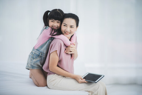 Asian Parent Mom And Dad With Female Chid Are Listening To Music With Wireless Headphones And Laptop At Home.