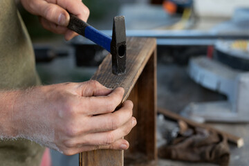 carpenters are preparing to hammer a nail into a wooden product, close up