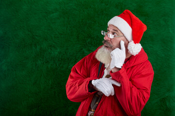 Mature bearded man with eyeglasses on face wearing Santa hat, Santa looks away at something, copy space