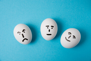 Eggs with faces and different emotions: anger, indifference and joy. Isolate on a blue background.