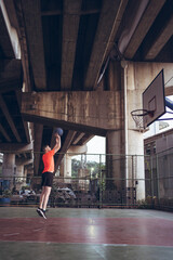 Caucasian young man playing basketball alone