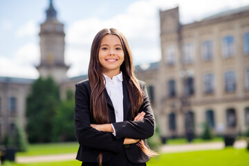 Photo of small pupil girl crossed hands beaming smile wear white shirt black jacket uniform urban outdoors