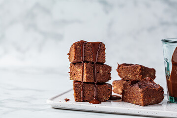 Stack of vegan brownies with dark chocolate on white board, white background, copy space. Vegan...