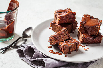 Vegan brownie squares with dark chocolate on gray plate, gray background. Vegan dessert concept.