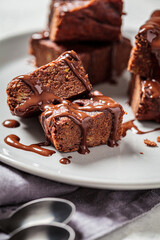 Vegan brownie squares with dark chocolate on gray plate, close-up. Vegan dessert concept.
