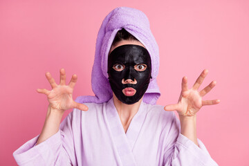 Close-up portrait of scary spooky housewife wearing towel turban black ugly clay mask pretending attack monster isolated over pink color background