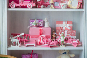 Christmas gifts in box on a shelf, pink car, airplane, wooden horse and gingle bell.
