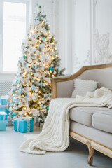 Calm image of interior luxury home living room decorated christmas tree and gifts, sofa covered with blanket. Selective focus