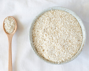 white sesame oilcake after oil making in bowl and wooden spoon on linen background. Benne oilcake. Top view.