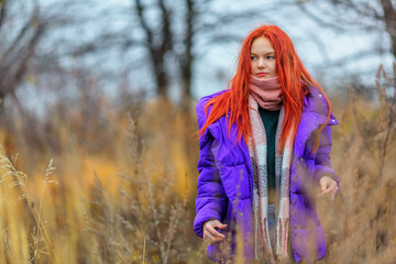 Teen girl in violet jacket in autumn day - 394995639