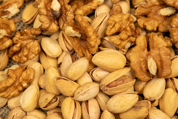 Pistachios and walnuts lie on the sacking. Close up.