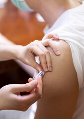 Doctor giving an injection to a male patient in the arm. Vaccine or flu shot in injection needle. Physician or nurse giving vaccination and immunity to virus, influenza or HPV, Covid 19, with syringe.
