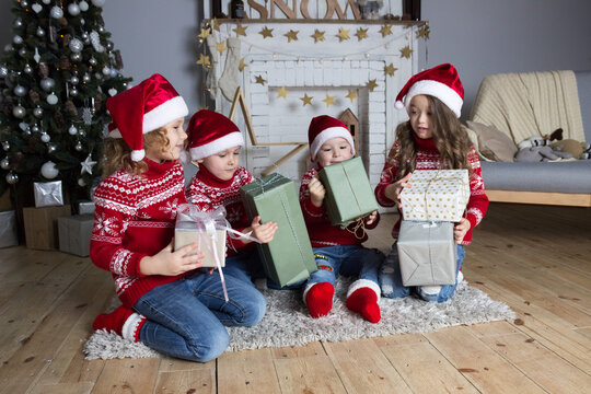 Merry christmas celebration santa hat kids in red sweaters opening gift boxes near new year decorated fireplace. Xmas children invitation card. Holiday greeting