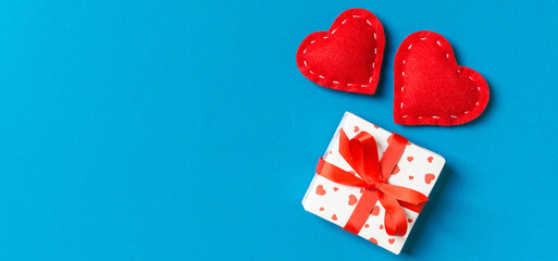 Fototapeta premium Top view of gift boxes and red textile hearts on colorful background. St Valentine's day concept with copy space