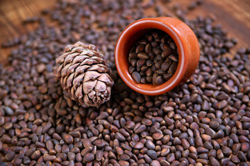 Fototapeta premium Composition with pine nuts and cones, clay and birch bark dishes on a wooden background.
