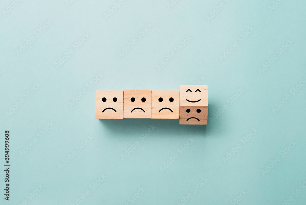 Poster flipping of wooden cube block from sad to smile emotion on blue background.