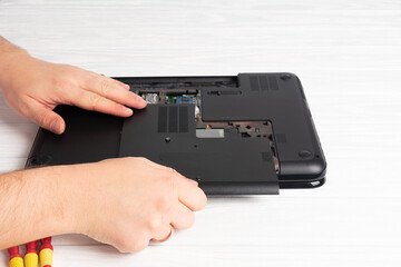 Laptop repair in the workshop. Computer repair technician working on a laptop with small tools.