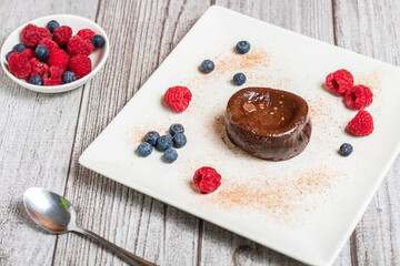 Chocolate coulant, with raspberries and blueberries decoration on a gray decoration background