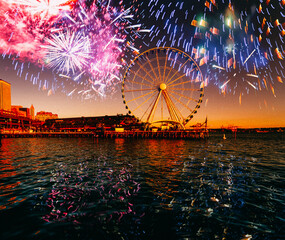 Cityscape with ferris wheel  illuminated at sunset with fireworks over sky near waterfront. Seattle, Washington, USA 