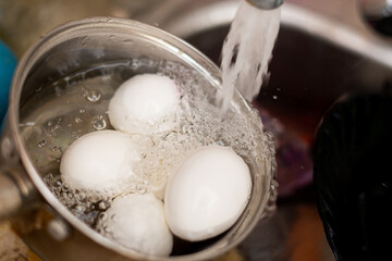 Cooling boiled eggs under running cold water.