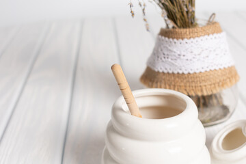White Jar with honey on a white background. Honey spoon in jar. Jar with honey. Honey spoon