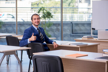 Young male teacher in suit in the classroom