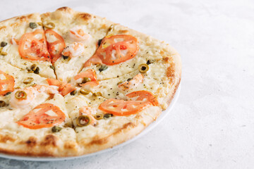 Pizza with tomatoes, cappers, shrimps, olives and parmesan close-up with place for text