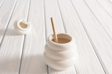 White Jar with honey on a white background. Honey spoon in jar. Jar with honey. Honey spoon