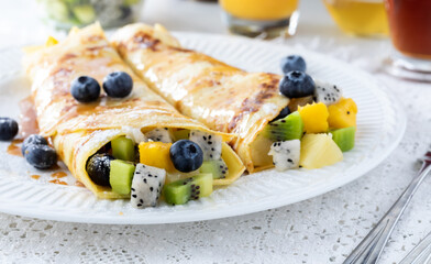 Close up of tropical fruit crepes filled with mango, dragon fruit and kiwi ready for eating.