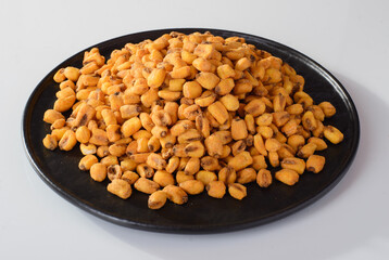 roasted salted corn on a round plate, beer snack isolated on white background