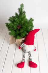 Obraz premium Christmas composition with gnome, gifts and festive decorations on a white background. New Year greeting card. Christmas gnome toy