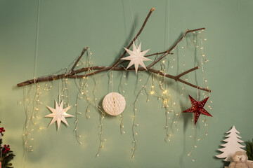 Christmas and New Year card. Beautiful author's decoration with Christmas balls on a wooden branch against the background of a green wall in hyuge style