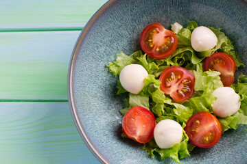 Italian caprese salad with mozzarella cheese, tomatoes and basil, in a plate. Top view