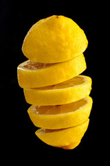 Fototapeta na wymiar Ripe lemon cut into slices and tossed into the air isolated on black background.