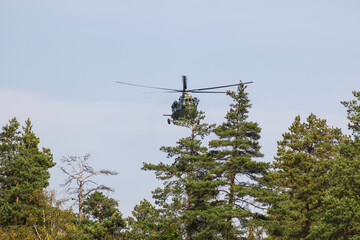 A military helicopter painted in camouflage color is flying high in the sky. Close up. 