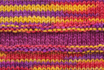 Knitted wool texture. Multicolored ornament - red, yellow, orange, purple.