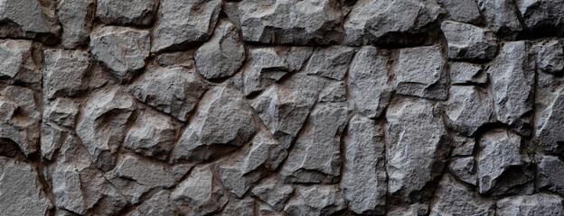 Dark masonry wall texture. Black stones and rocks of different shape, gray background, texture for interior and exterior design, narrow banner format