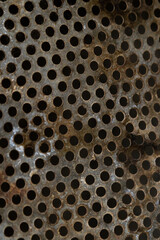 Selective focus on perforated metal sheet. Rusty texture with perforated holes metal corroded texture, rusty metal background perspective, texture for interior and exterior design, vertical photo