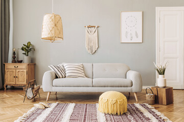 Stylish and design home interior of living room with gray sofa, wooden cubr , pillows, blankets, rattan lamp,  flowers, basket and elegant accessories. Stylish home decor. Template.