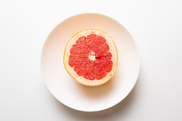 Fresh tasty grapefruit on plate. Half of grapefruit on white background