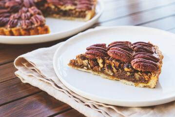 Piece of delicious freshly baked homemade pecan pie, close up. Popular holiday meal for Thanksgiving and Christmas.