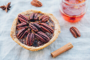 Delicious freshly baked homemade pecan pie on white tablecloth, close up. Sweet food from above. Popular holiday meal for Thanksgiving and Christmas.