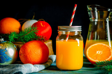 Christmas cocktail. Orange fresh in a glass jar with a tube stands on a wood table next to Christmas toys