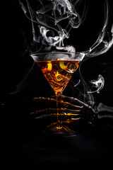 A skeleton hand holding a martini glass with eye balls and smoke in low key