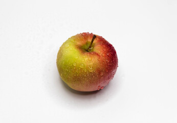 A fresh small Apple with water drops on the skin lies on a white background