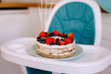 Children's high chair is decorated with blue and white balls to celebrate the first birthday